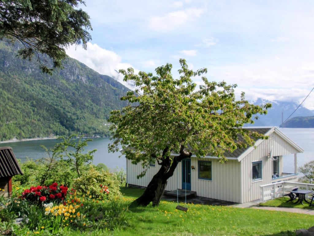 une maison avec un arbre à côté d'un lac dans l'établissement Chalet Kårahuset - FJH408 by Interhome, à Djønno