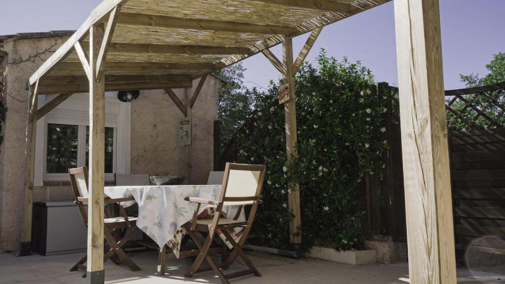 a wooden pergola with a table and chairs on a patio at une petite maison entre vignes et mer in Saint-Côme