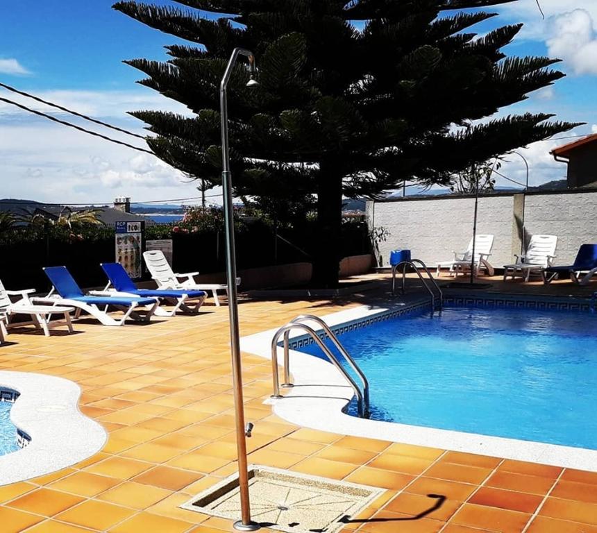 una piscina con sillas y un árbol al lado en Hotel Miramar 2** Superior, en A Lanzada