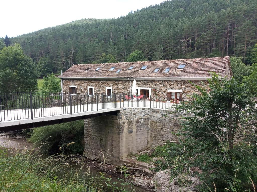 une maison en pierre avec un pont sur une rivière dans l'établissement Albergue Borda Nadal, à Ansó
