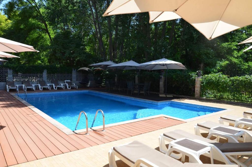 una piscina con sillas y sombrillas blancas en Park and pool family room en Nesebar