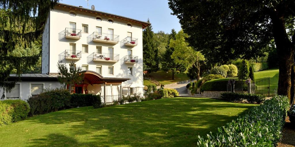 a large white building with a green lawn at Hotel Lilla' in Terlago