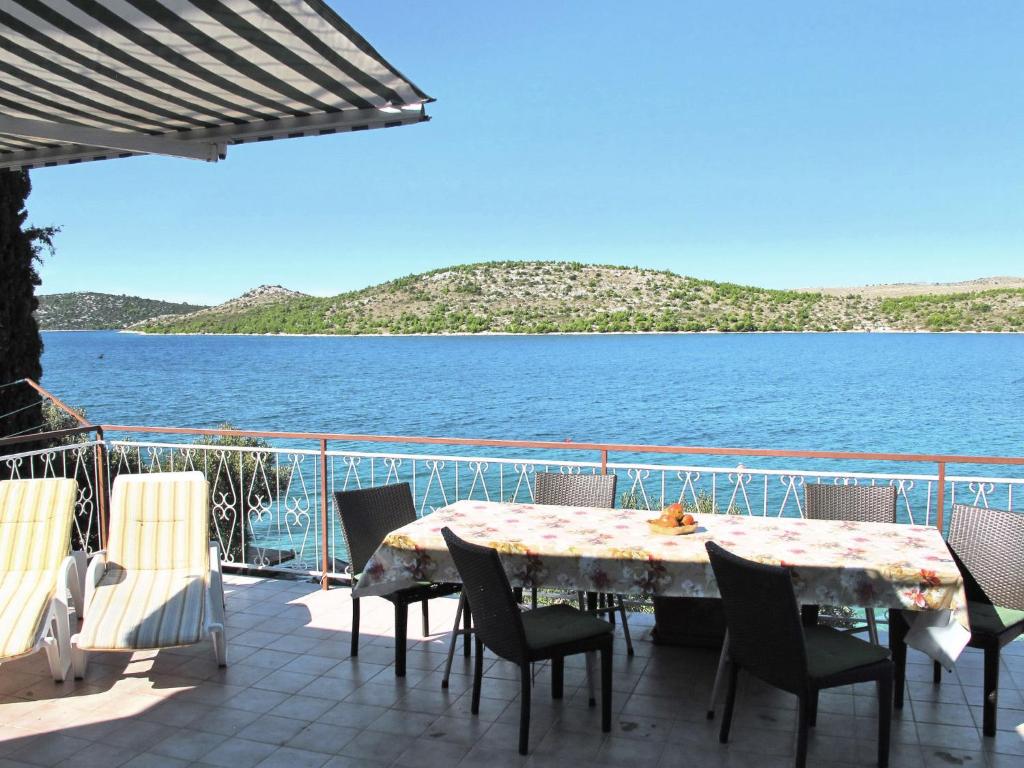 a table and chairs on a deck with a view of the water at Apartment Andriana - SIB225 by Interhome in Grebaštica