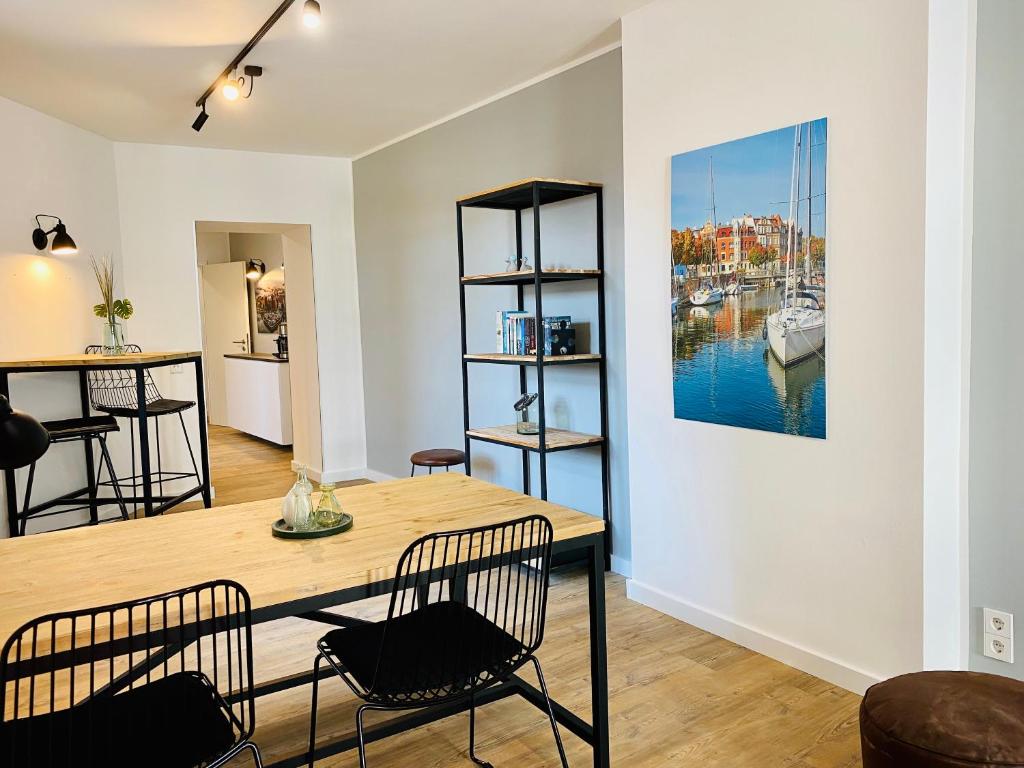 a dining room with a table and chairs and a painting on the wall at HafenCity Appartements Stralsund in Stralsund
