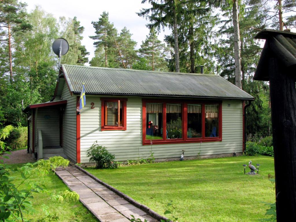 a small white house with red trim in a yard at Chalet Öja - HAL054 by Interhome in Oskarström