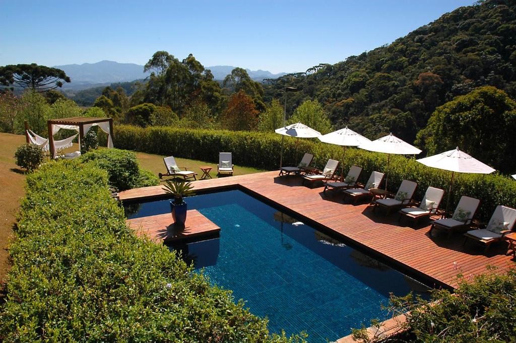 a swimming pool with lounge chairs and umbrellas next to at Pousada do Cedro in Santo Antônio do Pinhal