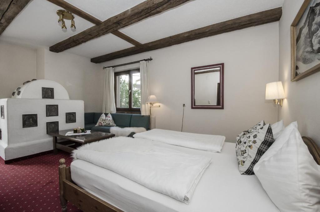 ein Schlafzimmer mit einem großen weißen Bett und ein Wohnzimmer in der Unterkunft DEP GÄSTEHAUS Residenz in Neukirchen am Großvenediger