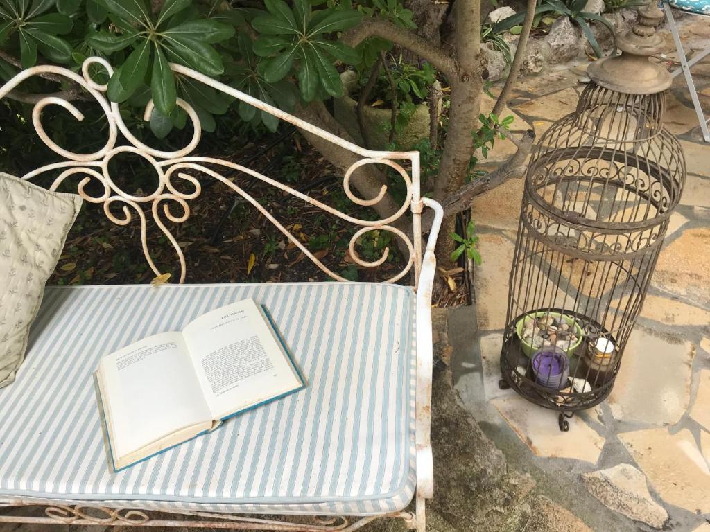 a bird cage with a book and a candle on a bench at "L'olivadou" ST JEAN CAP FERRAT in Saint-Jean-Cap-Ferrat
