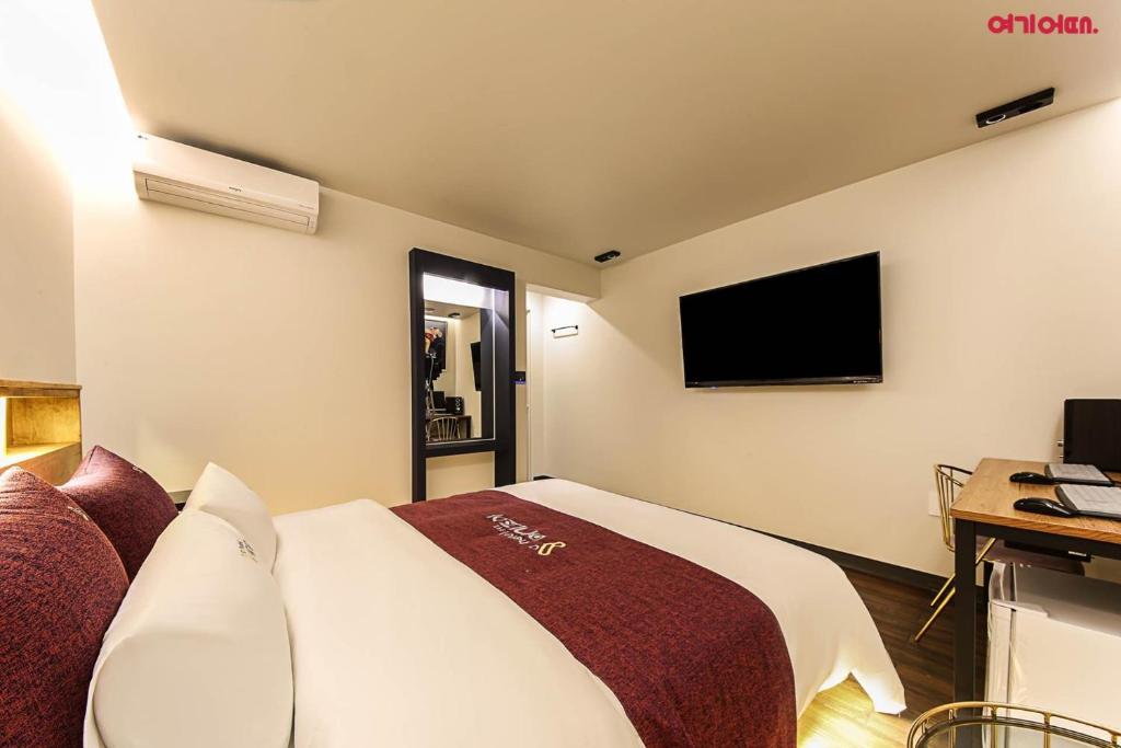 光州にあるHotel Yeogijoaのベッド1台、薄型テレビが備わるホテルルームです。