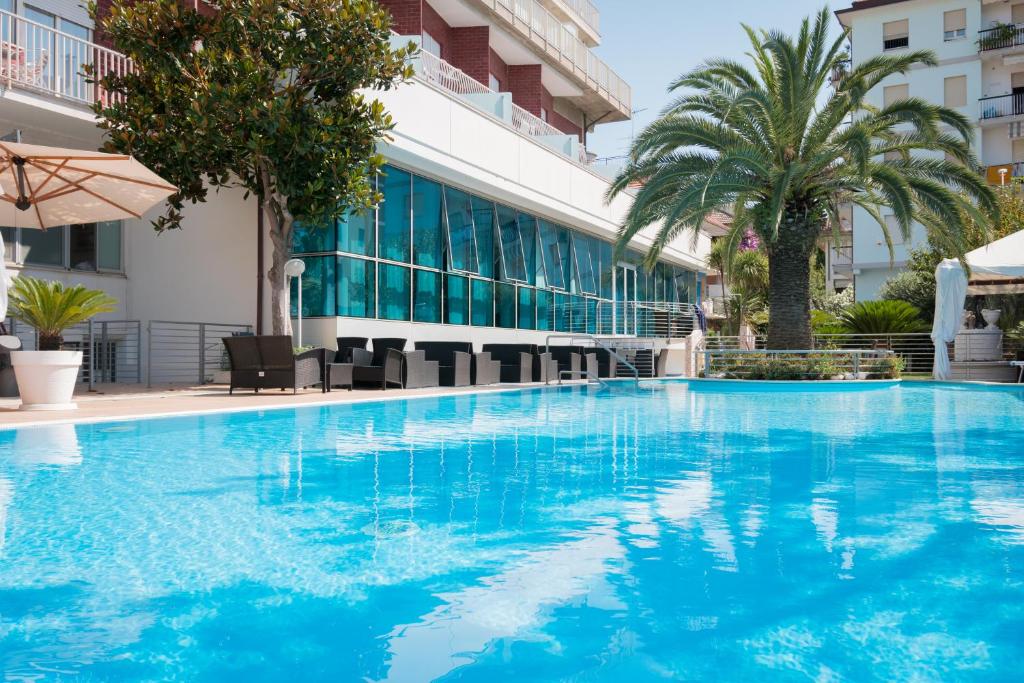 a large blue swimming pool in front of a building at Hotel Haus Charlotte in San Benedetto del Tronto