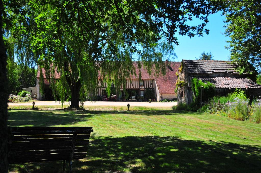 a building with a tree and a bench in a yard at LES GUENINS in Gien