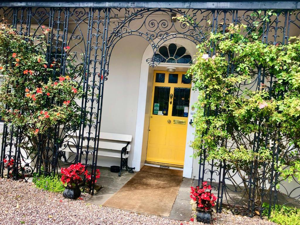 una porta gialla su un edificio con fiori e piante di Belvedere Lodge a Cork