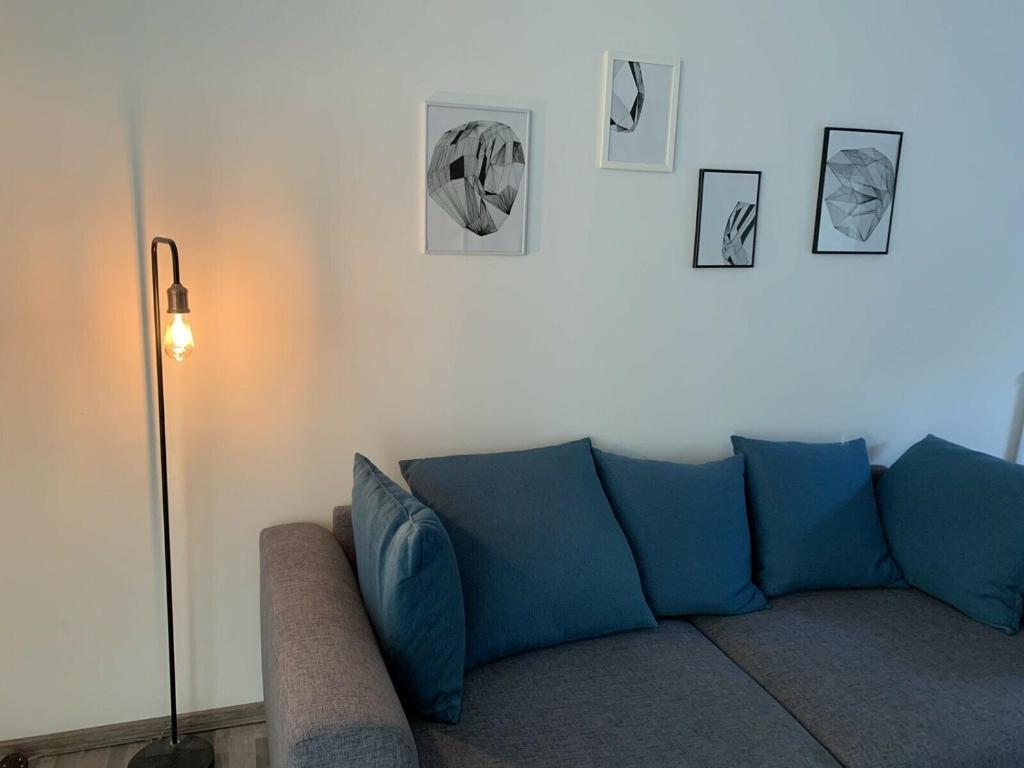 eine blaue Couch in einem Wohnzimmer mit Bildern an der Wand in der Unterkunft Großes, modernes Apartment im Souterrain in Frensdorf
