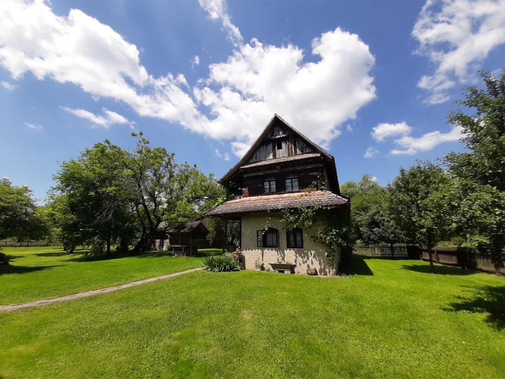 une ancienne maison sur un champ verdoyant avec un ciel dans l'établissement Ethno Village Stara Lonja, à Lonja