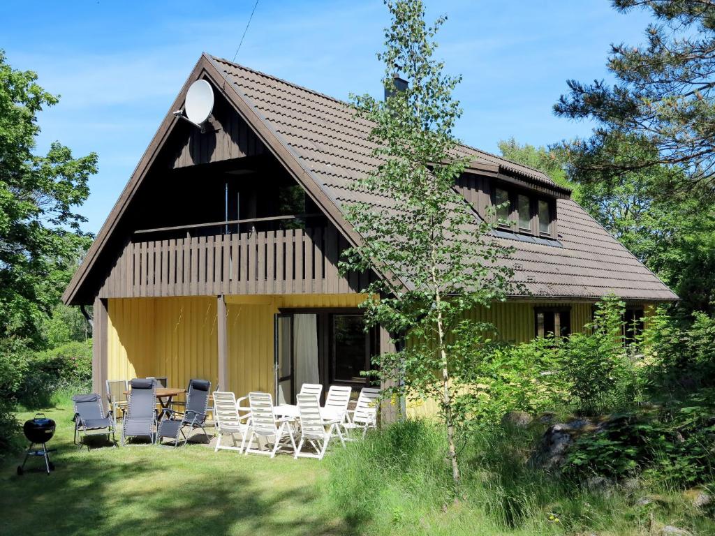 une maison jaune avec des chaises et un grill devant elle dans l'établissement Holiday Home Askerum - SND106 by Interhome, à Loftahammar