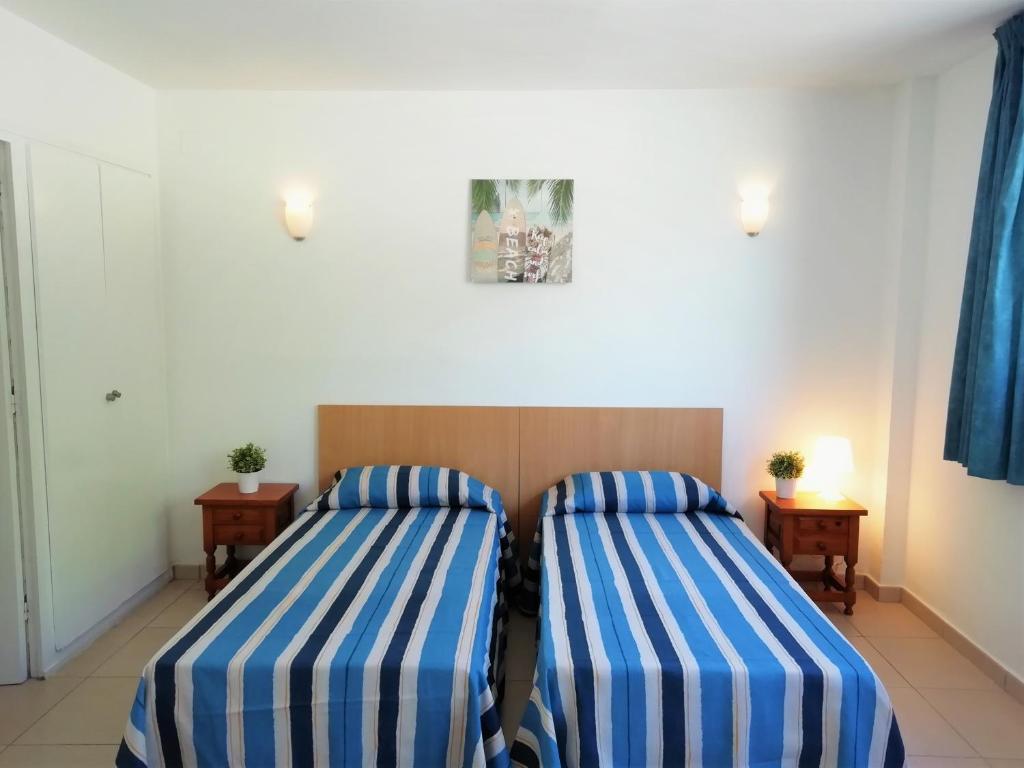 two beds in a room with blue and white stripes at Trill Mirasol C primera linea mar L'Estartit in L'Estartit