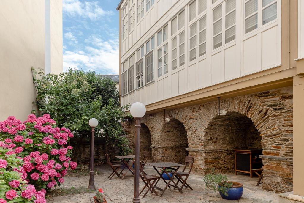 a patio with tables and flowers next to a building at Casa Soto By Teresa in Vegadeo