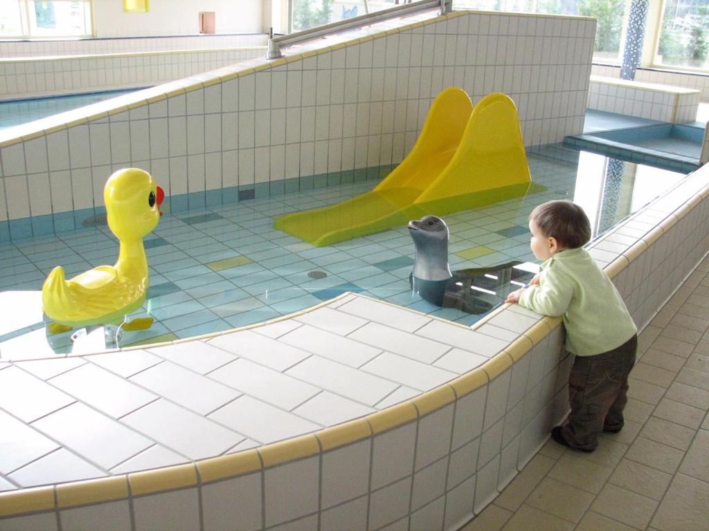 a young boy playing with toys in a swimming pool at Panorama Apartman in Velence