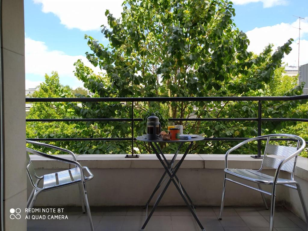 a table and chairs on a balcony with a tree at Le Jourdain in Paris