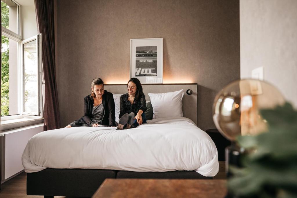 two women sitting on a bed in a bedroom at Monsieur Maurice in Bruges