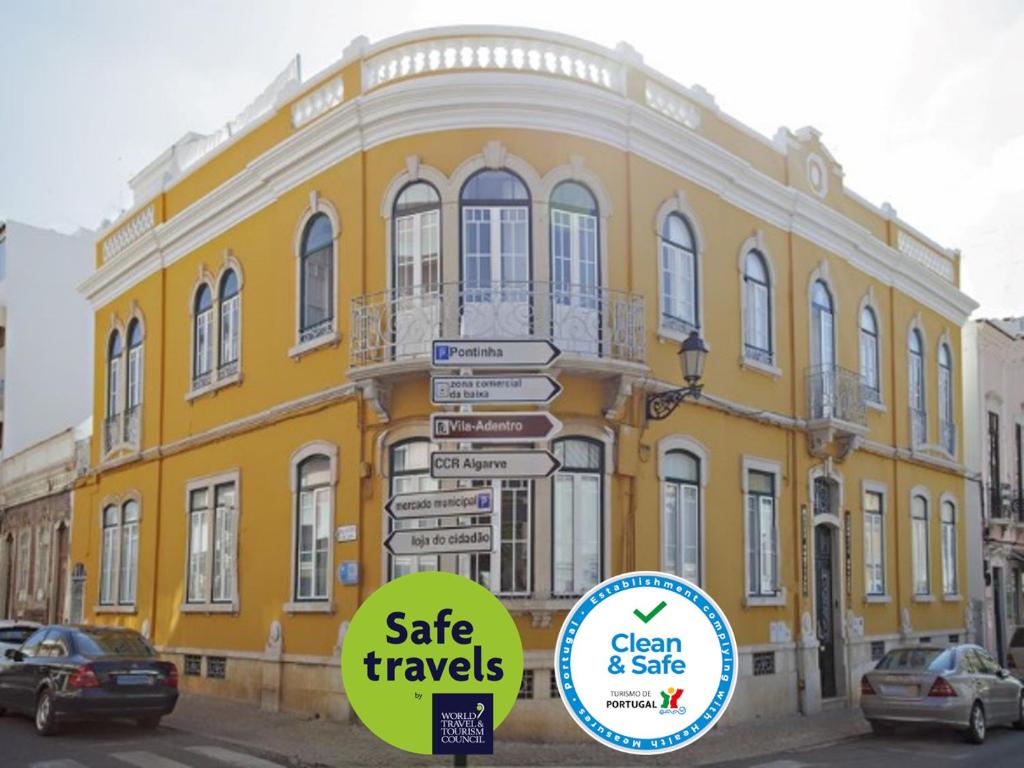 un bâtiment jaune avec des panneaux de rue devant lui dans l'établissement Baixa Terrace Hostel, à Faro