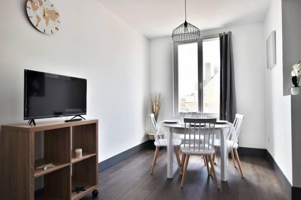 - une salle à manger avec une table, des chaises et une télévision dans l'établissement Le Cocon de Fort-Mahon, à Fort-Mahon-Plage