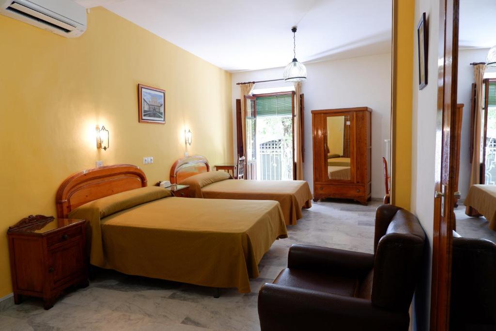 a hotel room with two beds and a chair at Hotel Central in Lanjarón