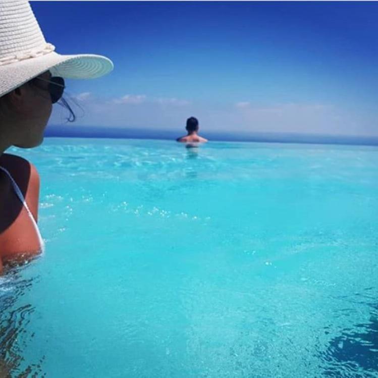 a woman in the water with a man in the ocean at Hotel Antica Cascina Del Golfo in Scopello