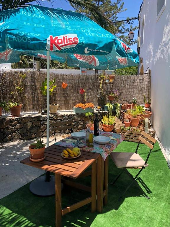a picnic table with an umbrella and fruits on it at CASA TAMARA APalmera BDátil in Haría