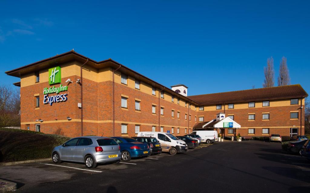 ein großes Gebäude mit Autos auf einem Parkplatz in der Unterkunft Holiday Inn Express Taunton East, an IHG Hotel in Taunton