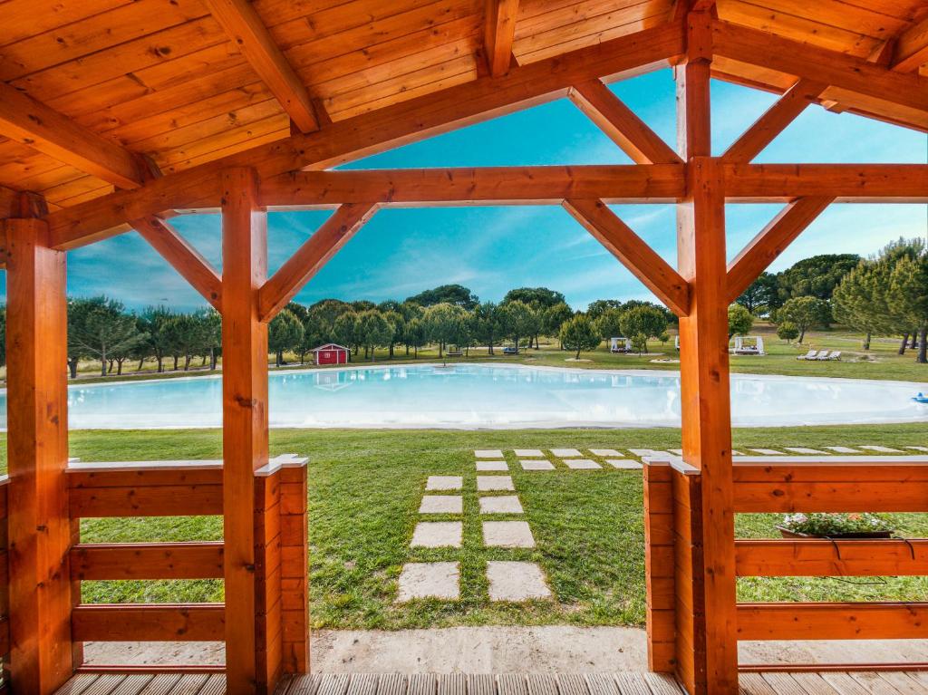 a wooden pavilion with a pool in a park at Chalet do Lago in Montargil