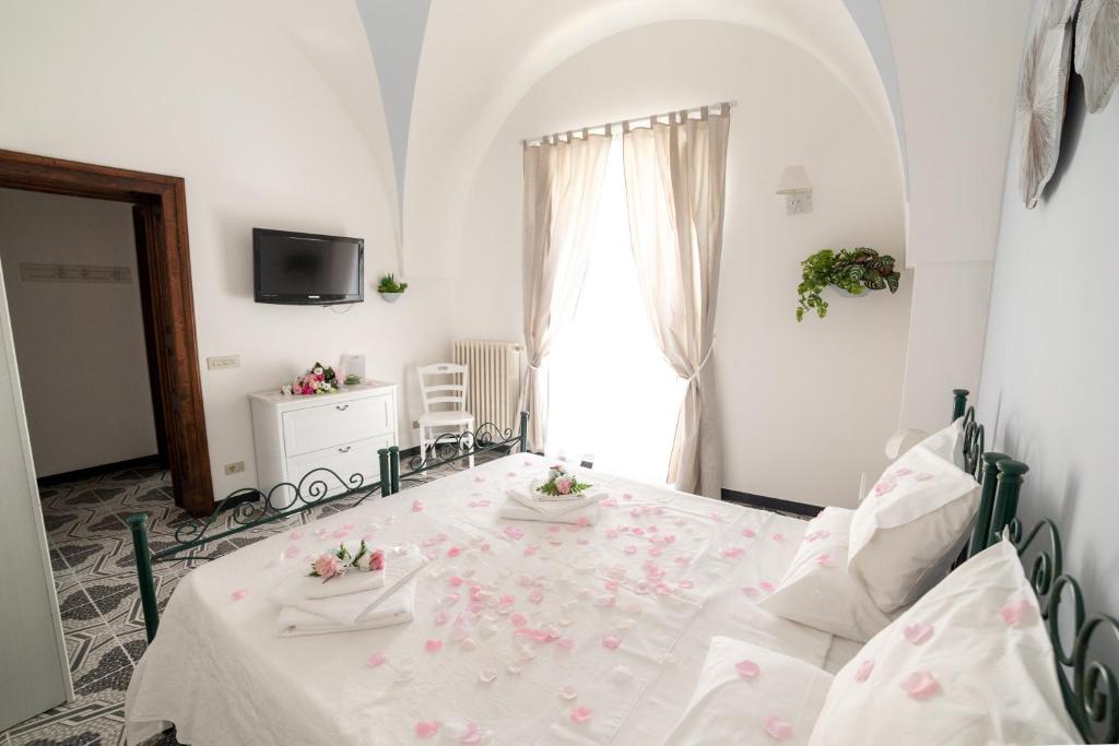 a white bedroom with a bed with flowers on it at Il Sogno Di Pandora in Castellana Grotte