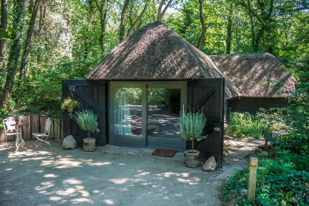 a small black shed with a thatch roof at Aa Casia vakantiehuis in Zeegse