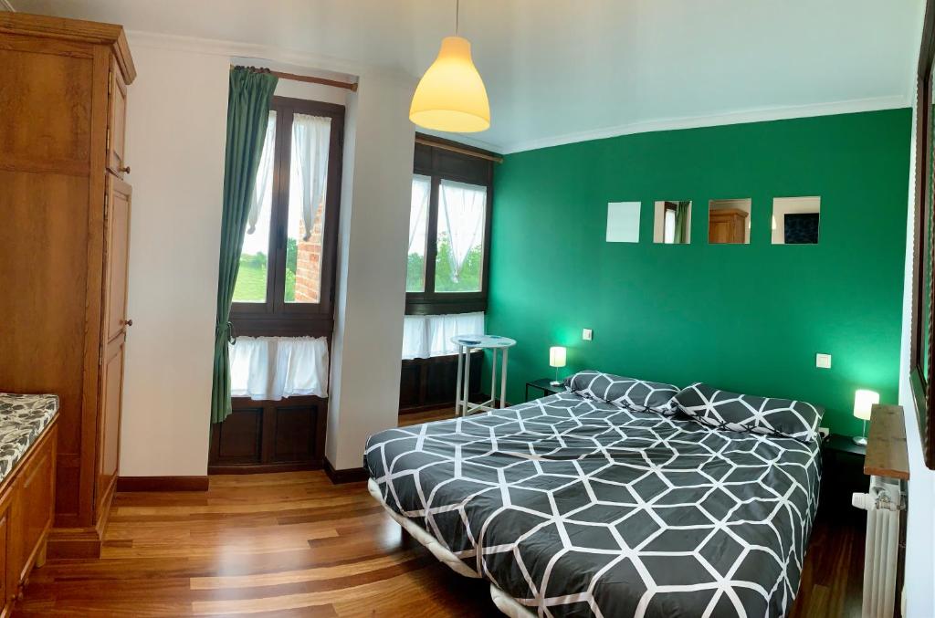 Dormitorio verde con cama con edredón blanco y negro en Apartamentos La Posada de Abanillas, en Abanillas