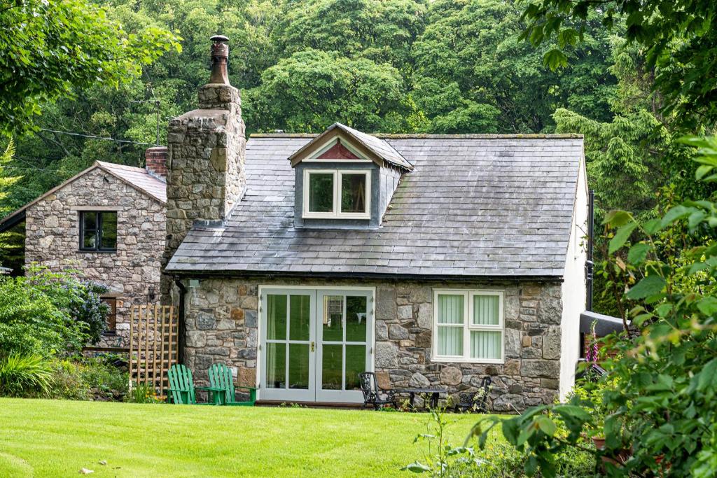 a stone house with a chimney on a lawn at Finest Retreats - The Cottage - Luxury 1 Bed Cottage in Rhydymwyn