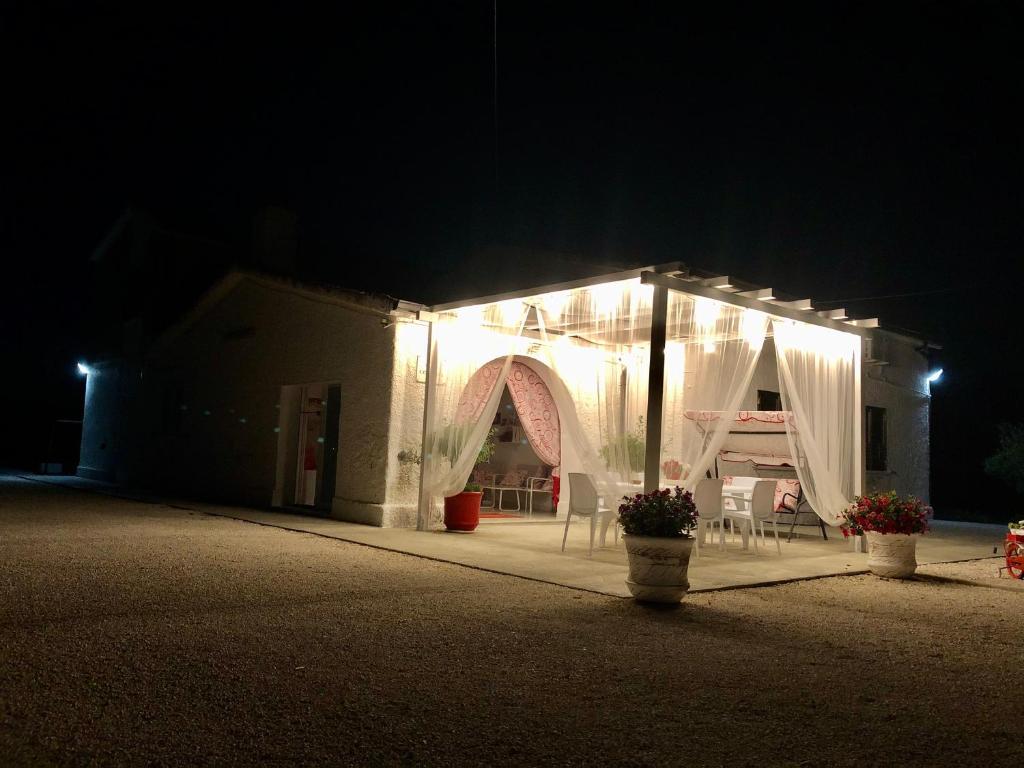 uma tenda iluminada à noite com cadeiras à frente em Villa Cenzina em Marina di Pisticci