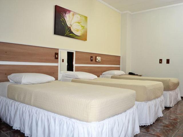 two beds in a hotel room with two beds at Perea Hotel in São Carlos