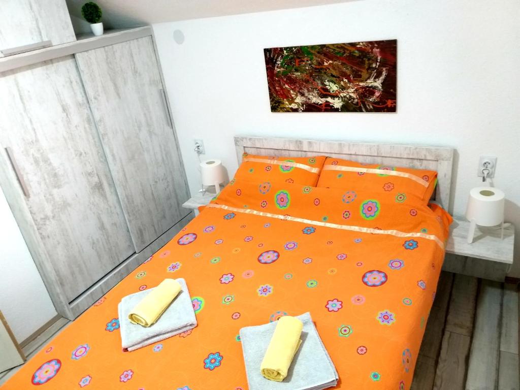 a bedroom with an orange bed with two towels on it at Apartmani Java in Soko Banja