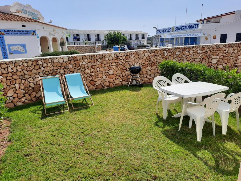 a table and chairs in a yard next to a stone wall at Apartamento en Arenal a 5 minutos de la playa in Arenal d'en Castell