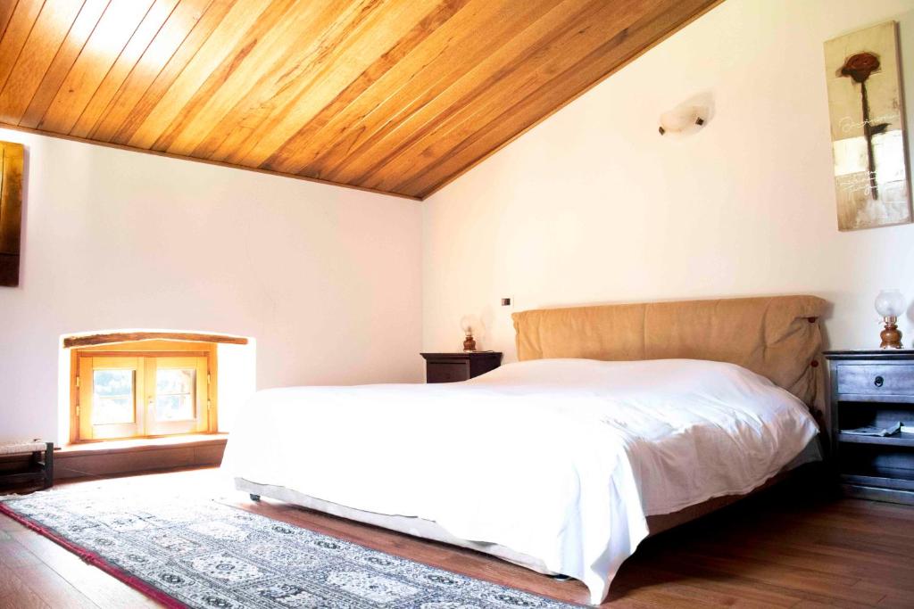 1 dormitorio con cama blanca y techo de madera en GARFAGNANA spazioso appartamento, relax! prenotaz min 3 giorni, en Piazza al Serchio