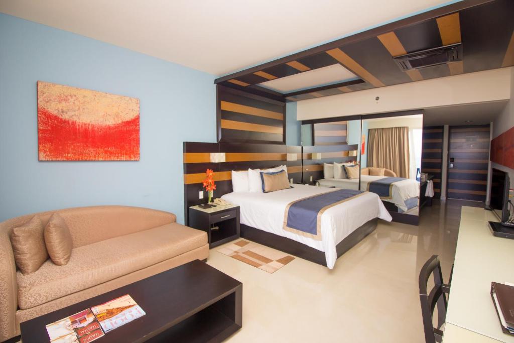 Habitación de hotel con 2 camas y sofá en Secrets Huatulco Resort & Spa, en Santa Cruz Huatulco