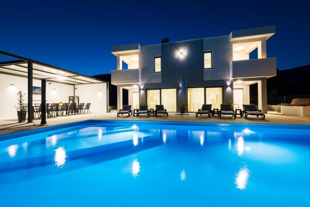 a large swimming pool in front of a house at night at Villa Sky - Heating Pool in Kastel Novi