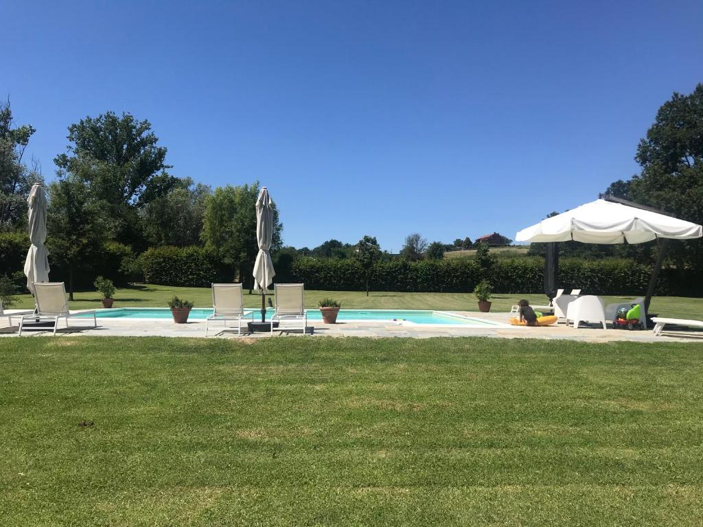 a pool with chairs and umbrellas in a yard at La Scuderia Charming Rooms in San Paolo Solbrito