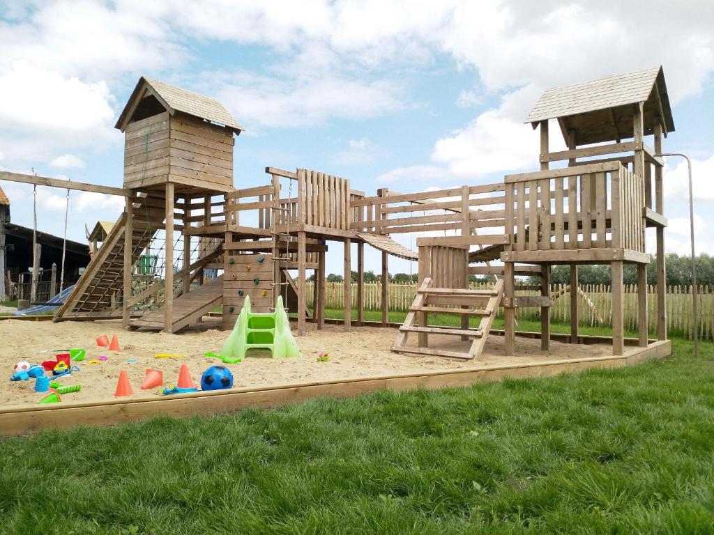 a playground with two wooden play equipment in the grass at De Calonne in Veurne