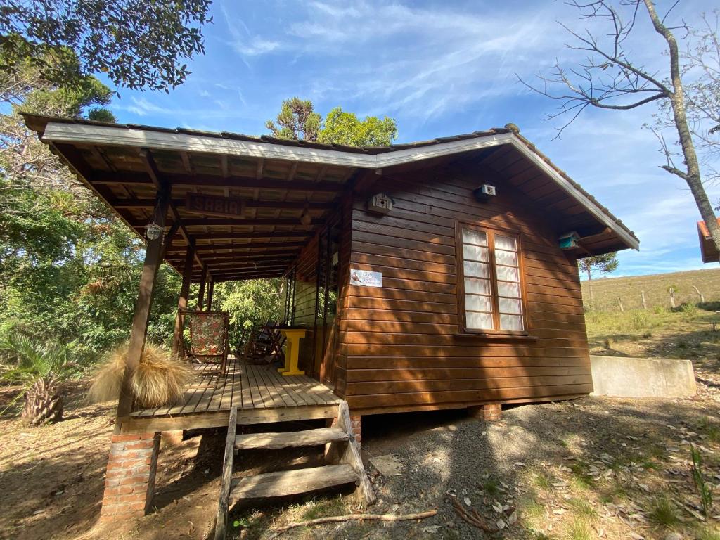 a small wooden cabin with a staircase in a field at Pousada Aguaraguazu in Tibagi