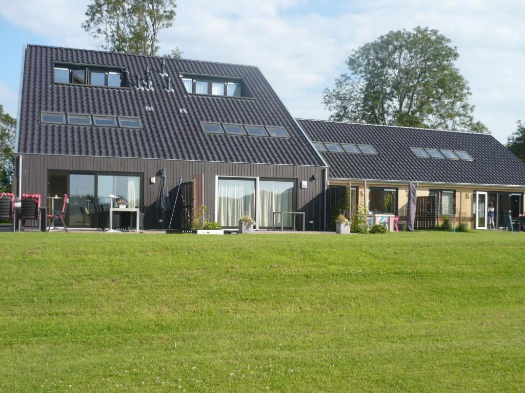 ein Haus mit großem Rasen davor in der Unterkunft Luxury holiday home with private terrace in Langweer