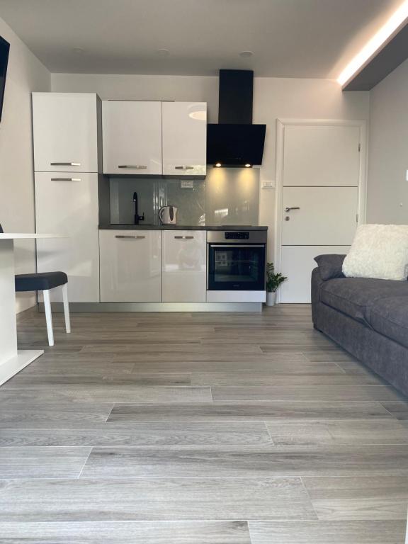Apartment Bono في باسكا فودا: مطبخ وغرفة معيشة مع دواليب بيضاء وأريكة