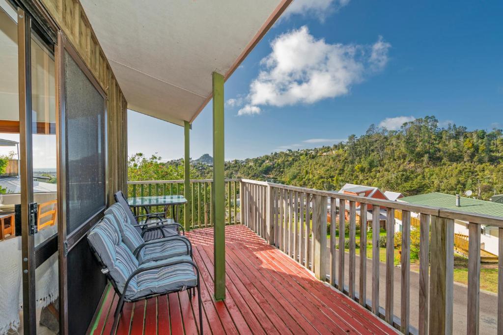 a balcony with chairs and a table on a deck at Coastal Hill Retreat - Tairua Holiday Home in Tairua