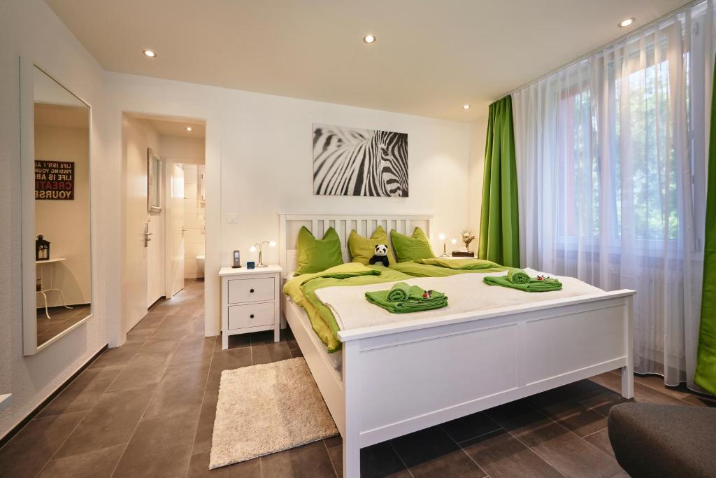 a bedroom with a large white bed with green pillows at da Maurizio Suites in Bern