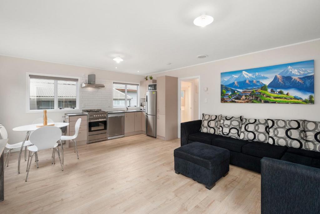 a living room with a black couch and a kitchen at Fifteen B - National Park Holiday Home in National Park